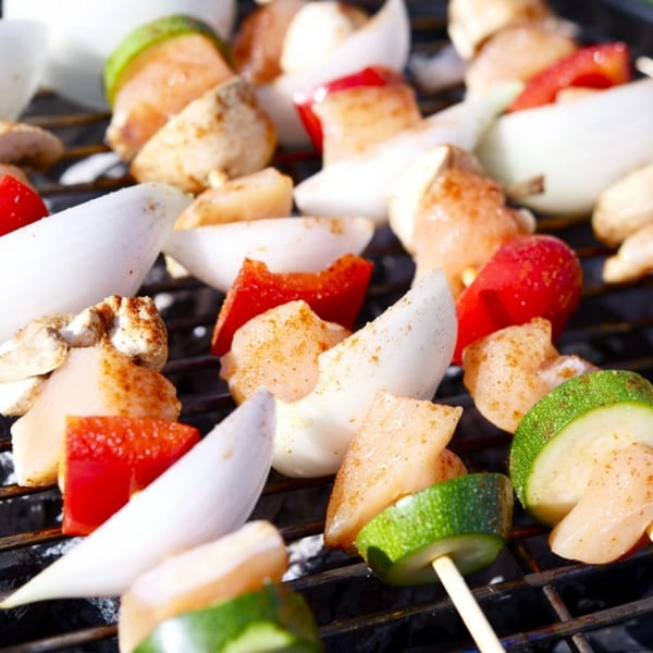 Chicken and vegetable kabobs with zucchini, red bell pepper, and onion grilling on a barbecue.